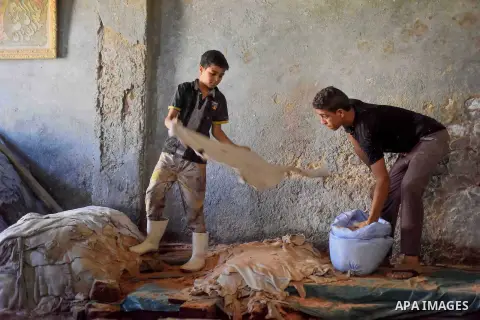 Egyptian leather tannery workers, salt the hides of animals before drying them, at a leather tannery, in Cairo, Egypt, on August 28, 2016. Photo by Amr Sayed