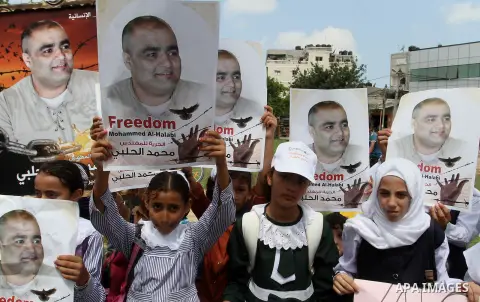 Palestinian demonstrators hold posters of Mohammad El Halabi, World Vision's manager of operations in Gaza who was accused by Israel of funnelling millions of dollars in aid money to Hamas, during a protest in solidarity...