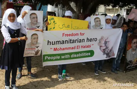 Palestinian demonstrators hold posters of Mohammad El Halabi, World Vision's manager of operations in Gaza who was accused by Israel of funnelling millions of dollars in aid money to Hamas, during a protest in solidarity...