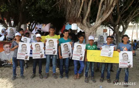 Palestinian demonstrators hold posters of Mohammad El Halabi, World Vision's manager of operations in Gaza who was accused by Israel of funnelling millions of dollars in aid money to Hamas, during a protest in solidarity...