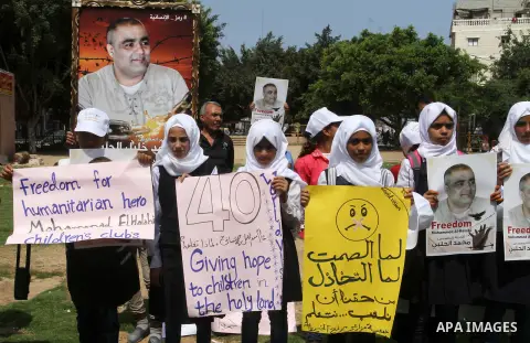 Palestinian demonstrators hold posters of Mohammad El Halabi, World Vision's manager of operations in Gaza who was accused by Israel of funnelling millions of dollars in aid money to Hamas, during a protest in solidarity...