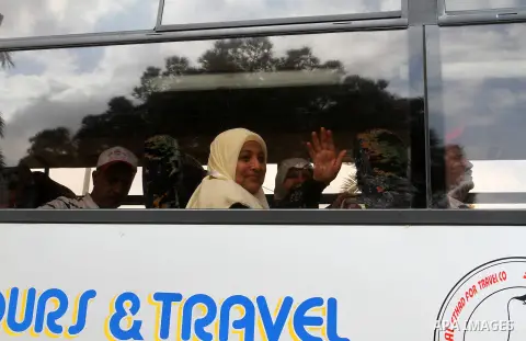 A Palestinian woman is seen through a broken window as she waits in a bus before leaving the Rafah border crossing between Egypt and the southern Gaza Strip, on August 31, 2016, ahead of her departure to the annual Hajj...