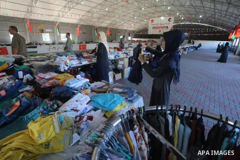 Palestinians wait to receive aid from the Turkish Red Crescent organization, "Eid clothes" ahead of Eid al-Adha in Gaza City, on Sept. 04, 2016. Photo by Mohammed Asad