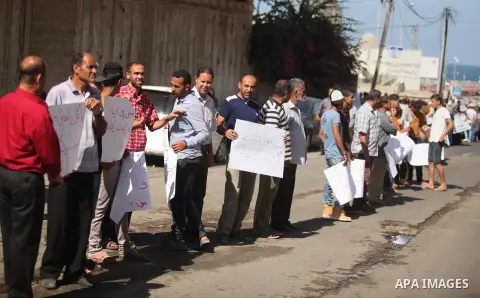 Palestinians from a human chain hold banners during a protest against Israeli attacks for fishermen, in Gaza city on September 8, 2016. Photo by Ashraf Amra