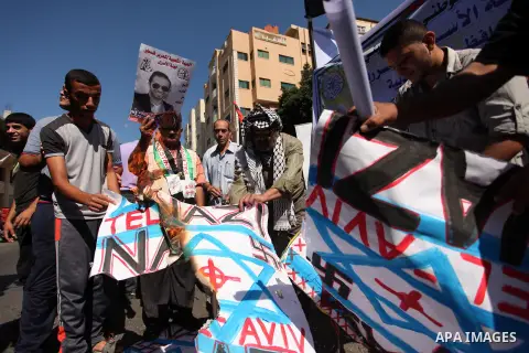 Palestinians burn posters bearing Israeli flag during a protest demanding release the prisoners in Israeli jails, in front of Red cross office in Gaza city, on Sept. 19, 2016. Photo by Ashraf Amra
