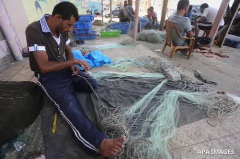 A Palestinian fisherman fixes a fishing net, at the beach in Gaza City, on Sept. 21, 2016. Photo by Mohammed Asad