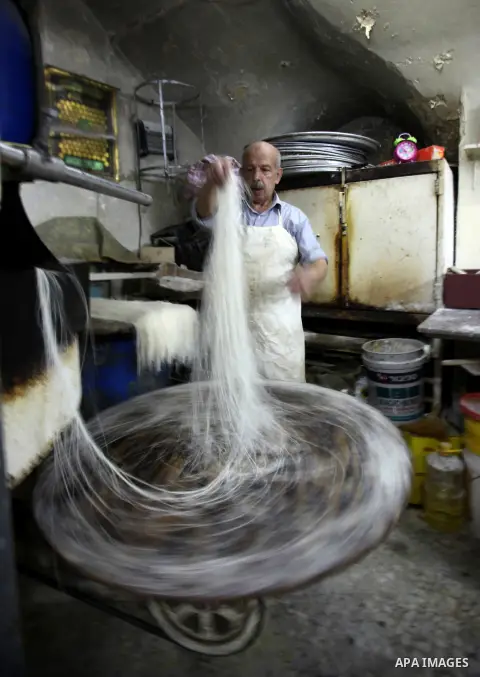 Palestinian Belal al-Zaqa, 64, prepares Kunafa, a traditional and favorite local sweet at his shop, in the West Bank city of Nablus on Sep. 29, 2016. Photo by Nedal Eshtayah