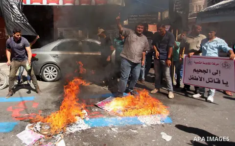 Palestinians burn a crossed poster of former Israeli President Shimon Peres, reading "murderer", during a rally following Friday prayers in Gaza City September 30, 2016. Photo by Ashraf Amra