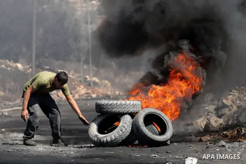 A Palestinian protester burns tires during clashes with Israeli security forces following a weekly demonstration against the expropriation of Palestinian land by Israel on Sep. 30, 2016, in the village of Kfar Qaddum, ne...
