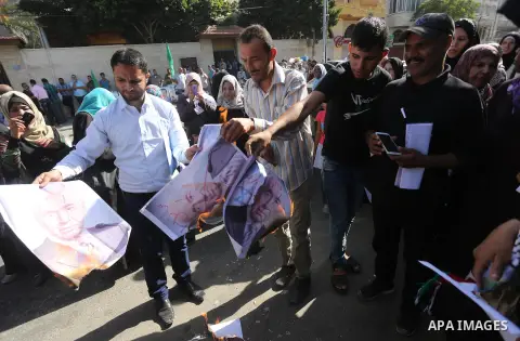 Palestinians burn posters of former Israeli President Shimon Peres during a protest, in front of Red cross office in Gaza city, on Oct. 03, 2016. Photo by Mohammed Asad