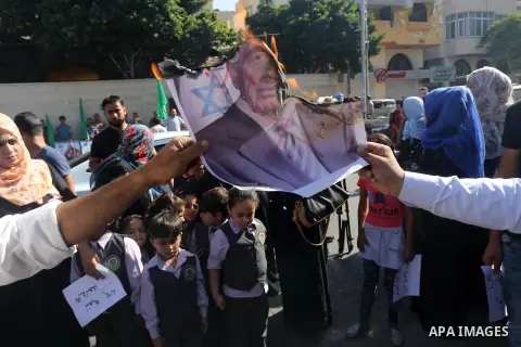 Palestinians burn posters of former Israeli President Shimon Peres during a protest, in front of Red cross office in Gaza city, on Oct. 03, 2016. Photo by Mohammed Asad