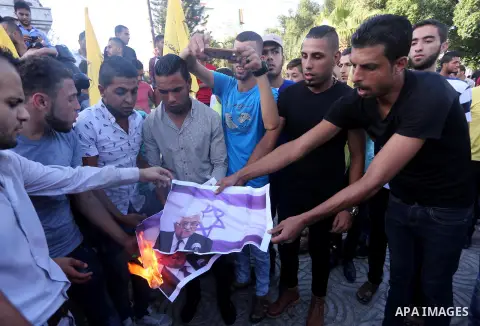 Palestinians who support Palestinian senior Fatah official Mohammed Dahlan burn crossed posters of Palestinian President Mahmoud Abbas and Israeli flags during a protest in Gaza City on Oct. 06, 2016. Photo by Mohammed A...