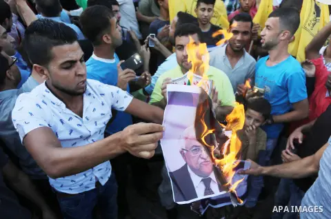 Palestinians who support Palestinian senior Fatah official Mohammed Dahlan burn crossed posters of Palestinian President Mahmoud Abbas and Israeli flags during a protest in Gaza City on Oct. 06, 2016. Photo by Mohammed A...