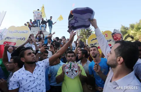 Palestinians who support Palestinian senior Fatah official Mohammed Dahlan burn crossed posters of Palestinian President Mahmoud Abbas and Israeli flags during a protest in Gaza City on Oct. 06, 2016. Photo by Mohammed A...