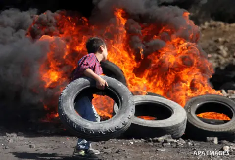 A Palestinian protester burns tires during clashes with Israeli security forces following a weekly demonstration against the expropriation of Palestinian land by Israel on October 6, 2016, in the village of Kfar Qaddum,...