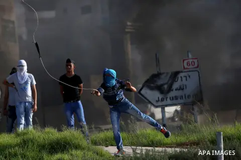 A Palestinian protester uses a slingshot to hurl stones towards Israeli border policemen during clashes in the West Bank town of Al-Ram, near Jerusalem October 9, 2016. A Palestinian opened fire from a car in Jerusalem o...