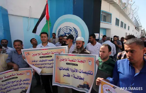Palestinians hold banners during a protest against the UNRWA decision to reduce of the aid in front of the headquarters United Nations Relief and Works Agency (UNRWA), in Gaza city on October 11, 2016. Photo by Ashraf Am...