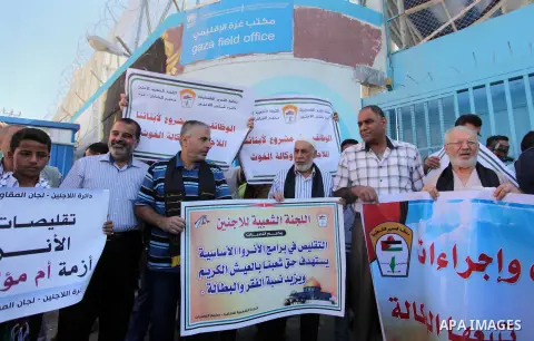Palestinians hold banners during a protest against the UNRWA decision to reduce of the aid in front of the headquarters United Nations Relief and Works Agency (UNRWA), in Gaza city on October 11, 2016. Photo by Ashraf Am...