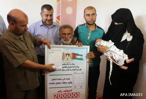 Members of the Interior Ministry in Gaza offer a certificate to Jihad and Tahany Shaath marking the birth of their son Waleed who is the two millionth baby to be born in Gaza at their house in the southern Gaza Strip tow...