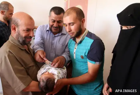 Members of the Interior Ministry in Gaza offer a certificate to Jihad and Tahany Shaath marking the birth of their son Waleed who is the two millionth baby to be born in Gaza at their house in the southern Gaza Strip tow...