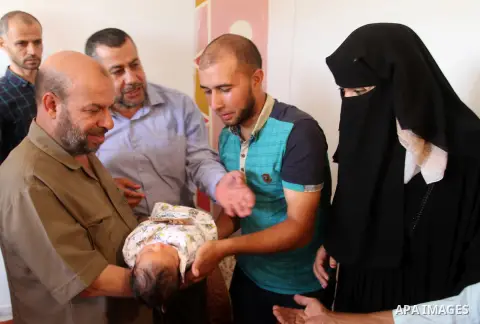 Members of the Interior Ministry in Gaza offer a certificate to Jihad and Tahany Shaath marking the birth of their son Waleed who is the two millionth baby to be born in Gaza at their house in the southern Gaza Strip tow...