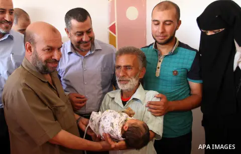 Members of the Interior Ministry in Gaza offer a certificate to Jihad and Tahany Shaath marking the birth of their son Waleed who is the two millionth baby to be born in Gaza at their house in the southern Gaza Strip tow...