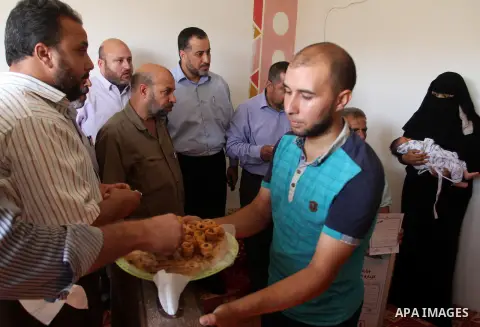 Members of the Interior Ministry in Gaza offer a certificate to Jihad and Tahany Shaath marking the birth of their son Waleed who is the two millionth baby to be born in Gaza at their house in the southern Gaza Strip tow...