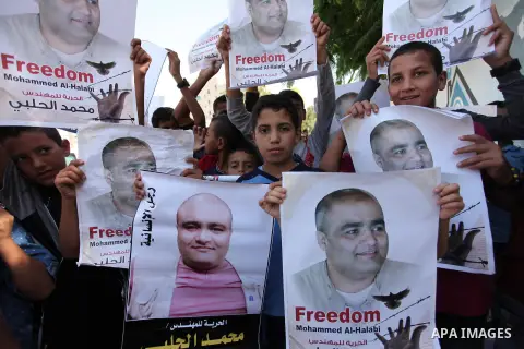 Palestinian boys hold posters of Mohammad El Halabi, World Vision's manager of operations in Gaza who was accused by Israel of funnelling millions of dollars in aid money to Hamas, during a protest in solidarity with El...