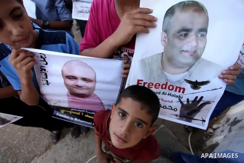 Palestinian boys hold posters of Mohammad El Halabi, World Vision's manager of operations in Gaza who was accused by Israel of funnelling millions of dollars in aid money to Hamas, during a protest in solidarity with El...