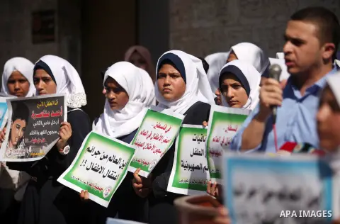 Palestinian students hold banners during a protest to show solidarity with the child prisoners in Israeli jails, in front of Red cross office in Gaza city, on October 13, 2016. Photo by Ashraf Amra
