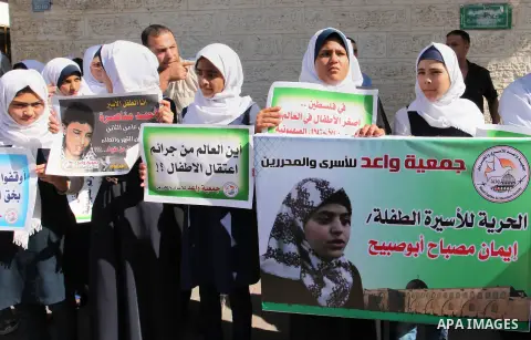 Palestinian students hold banners during a protest to show solidarity with the child prisoners in Israeli jails, in front of Red cross office in Gaza city, on October 13, 2016. Photo by Ashraf Amra