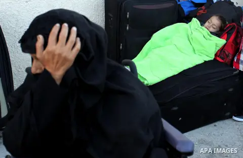 A Palestinian girl sleeps on a suitcase as she waits with her family for a travel permit to cross into Egypt through the Rafah border crossing on October 15, 2016 in the southern Gaza Strip. Egyptian authorities temporar...