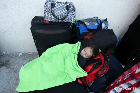 A Palestinian girl sleeps on a suitcase as she waits with her family for a travel permit to cross into Egypt through the Rafah border crossing on October 15, 2016 in the southern Gaza Strip. Egyptian authorities temporar...
