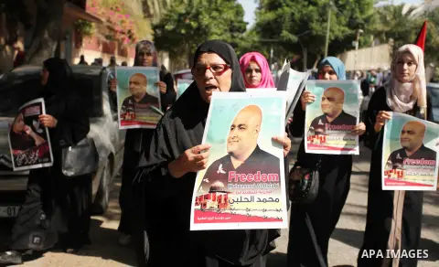Palestinians hold posters of Mohammad El Halabi, World Vision's manager of operations in Gaza who was accused by Israel of funnelling millions of dollars in aid money to Hamas, during a protest in solidarity with El Hala...
