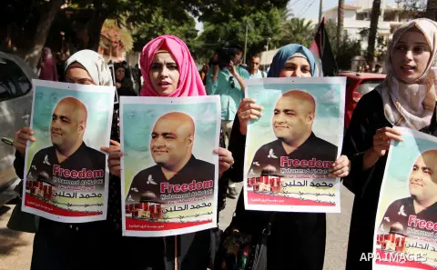 Palestinians hold posters of Mohammad El Halabi, World Vision's manager of operations in Gaza who was accused by Israel of funnelling millions of dollars in aid money to Hamas, during a protest in solidarity with El Hala...