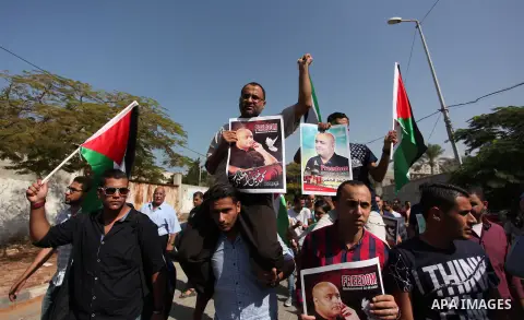 Palestinians hold posters of Mohammad El Halabi, World Vision's manager of operations in Gaza who was accused by Israel of funnelling millions of dollars in aid money to Hamas, during a protest in solidarity with El Hala...