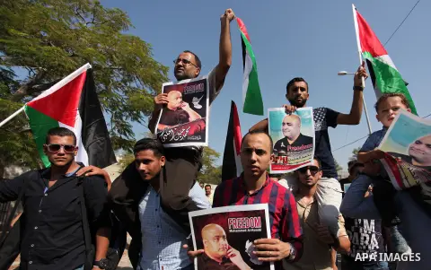 Palestinians hold posters of Mohammad El Halabi, World Vision's manager of operations in Gaza who was accused by Israel of funnelling millions of dollars in aid money to Hamas, during a protest in solidarity with El Hala...