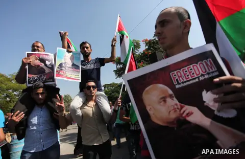 Palestinians hold posters of Mohammad El Halabi, World Vision's manager of operations in Gaza who was accused by Israel of funnelling millions of dollars in aid money to Hamas, during a protest in solidarity with El Hala...