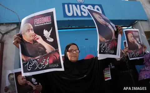 Palestinians hold posters of Mohammad El Halabi, World Vision's manager of operations in Gaza who was accused by Israel of funnelling millions of dollars in aid money to Hamas, during a protest in solidarity with El Hala...