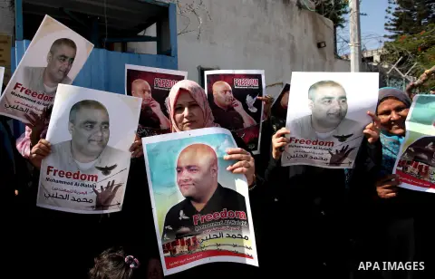 Palestinians hold posters of Mohammad El Halabi, World Vision's manager of operations in Gaza who was accused by Israel of funnelling millions of dollars in aid money to Hamas, during a protest in solidarity with El Hala...