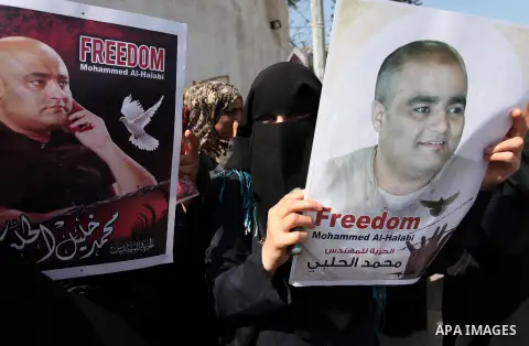 Palestinians hold posters of Mohammad El Halabi, World Vision's manager of operations in Gaza who was accused by Israel of funnelling millions of dollars in aid money to Hamas, during a protest in solidarity with El Hala...
