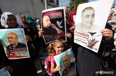 Palestinians hold posters of Mohammad El Halabi, World Vision's manager of operations in Gaza who was accused by Israel of funnelling millions of dollars in aid money to Hamas, during a protest in solidarity with El Hala...