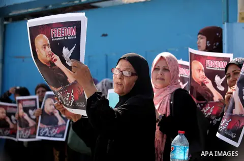 Palestinians hold posters of Mohammad El Halabi, World Vision's manager of operations in Gaza who was accused by Israel of funnelling millions of dollars in aid money to Hamas, during a protest in solidarity with El Hala...