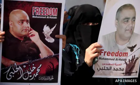 Palestinians hold posters of Mohammad El Halabi, World Vision's manager of operations in Gaza who was accused by Israel of funnelling millions of dollars in aid money to Hamas, during a protest in solidarity with El Hala...