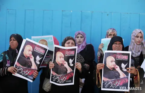 Palestinians hold posters of Mohammad El Halabi, World Vision's manager of operations in Gaza who was accused by Israel of funnelling millions of dollars in aid money to Hamas, during a protest in solidarity with El Hala...