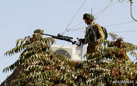 A member of Israeli security forces stands guard as Israeli settlers walk to visit the Jewish shrine of Atnaeil Ben Kinaz during the Jewish Sukkot holiday or the feast of the Tabernacles in a Palestinian neighbourhood of...