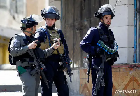Israeli soldiers stand guard as Israeli settlers walk to visit the Jewish shrine of Atnaeil Ben Kinaz during the Jewish Sukkot holiday or the feast of the Tabernacles in a Palestinian neighbourhood of the divided West Ba...