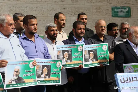 Palestinian members of Hamas legislative council and members of the factions hold banners during a protest to show solidarity with Leader of the northern Islamic Movement Sheikh Raed Salah who is in solitary confinement...