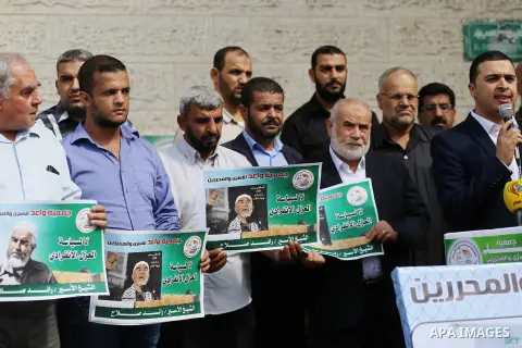 Palestinian members of Hamas legislative council and members of the factions hold banners during a protest to show solidarity with Leader of the northern Islamic Movement Sheikh Raed Salah who is in solitary confinement...