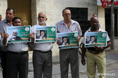 Palestinian members of Hamas legislative council and members of the factions hold banners during a protest to show solidarity with Leader of the northern Islamic Movement Sheikh Raed Salah who is in solitary confinement...